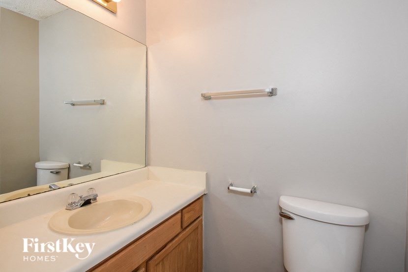 A bathroom with a sink, toilet and mirror.