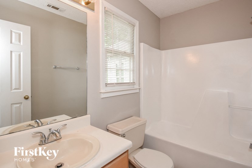 A bathroom with a white toilet, sink, and bathtub.