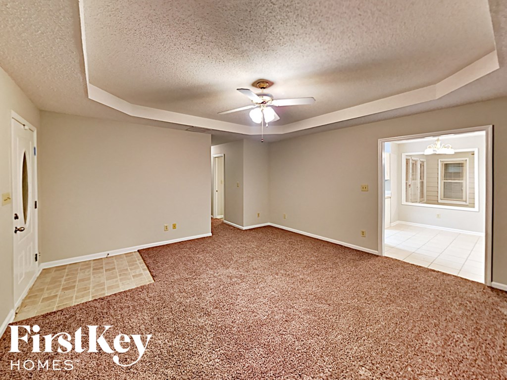 A room with a carpeted floor and a ceiling fan.