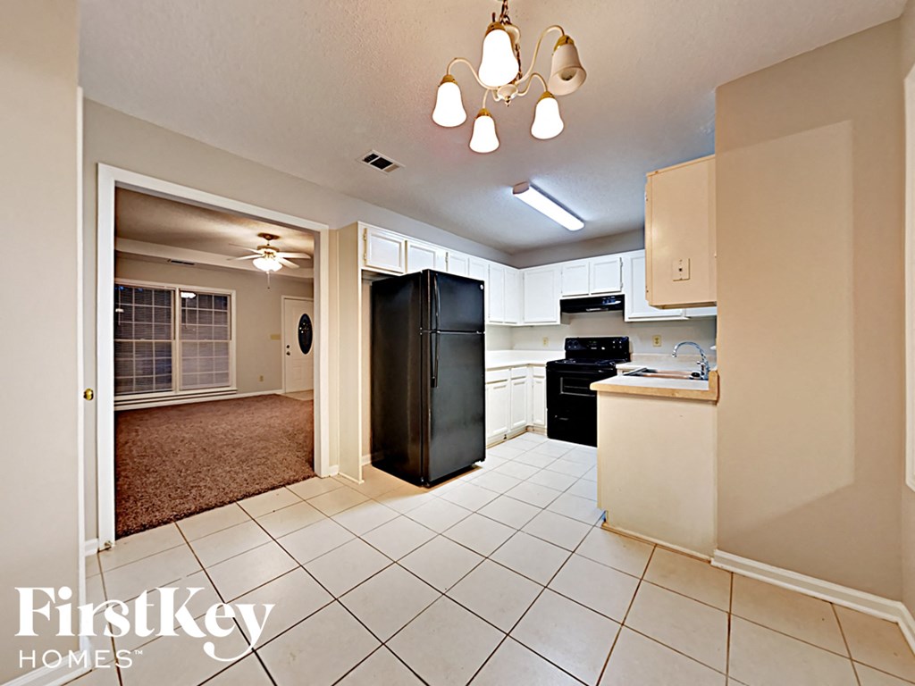 A kitchen with a black fridge and white cabinets.