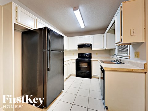 A kitchen with a black refrigerator and a black oven.
