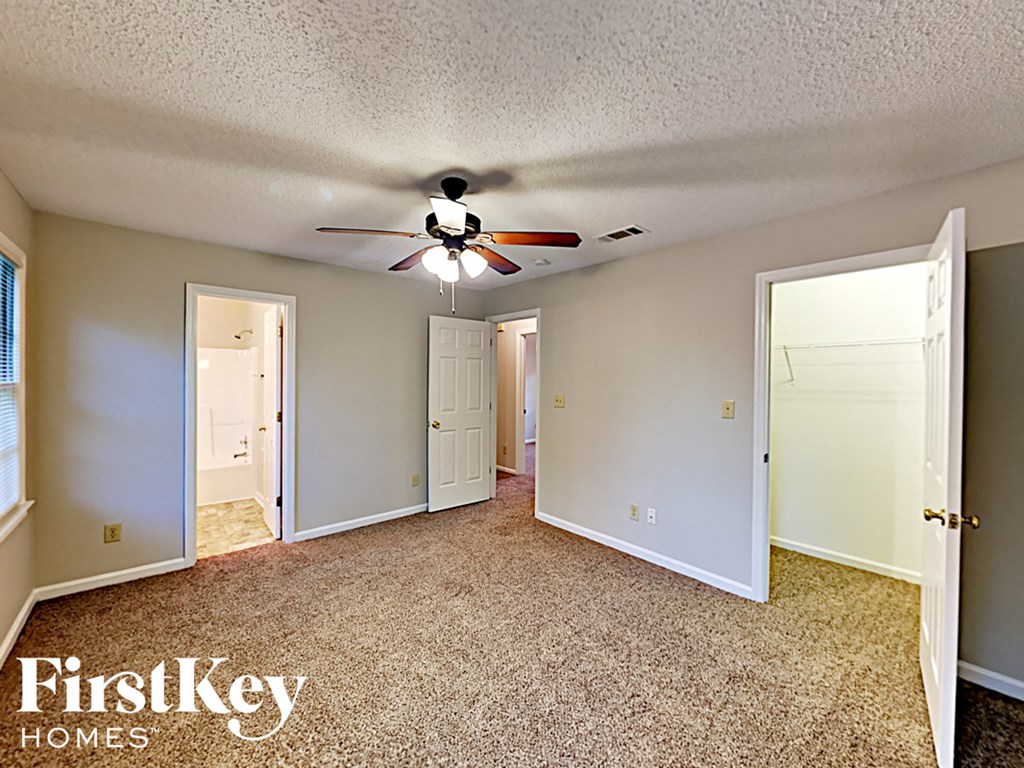 A spacious room with a ceiling fan and carpeted floor.