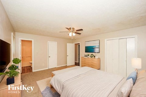 A bedroom with a large bed and a ceiling fan.