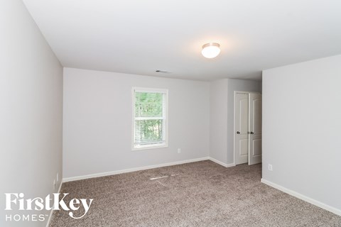a bedroom with white walls and carpet and a window