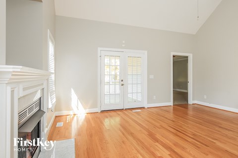 a living room with a fireplace and a door to a room with wood floors