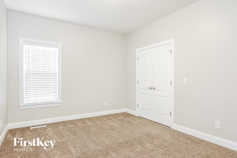a bedroom with a door and a carpeted floor