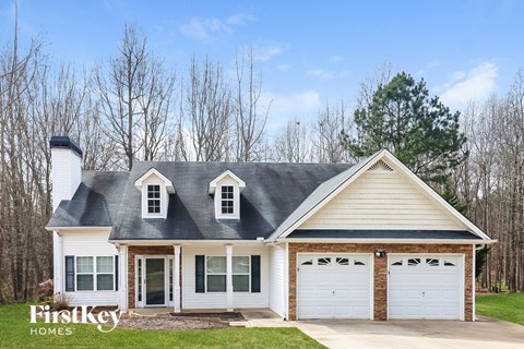 a white house with white garage doors and a gray roof