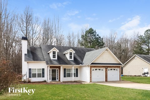 a white house with a gray roof and white garage doors