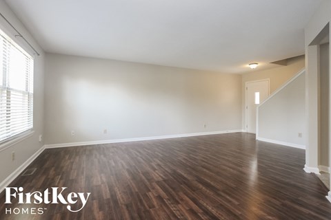 the spacious living room with wood flooring and white walls
