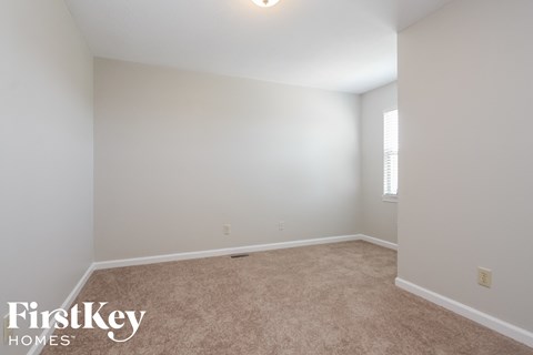 a bedroom with white walls and carpet and a window