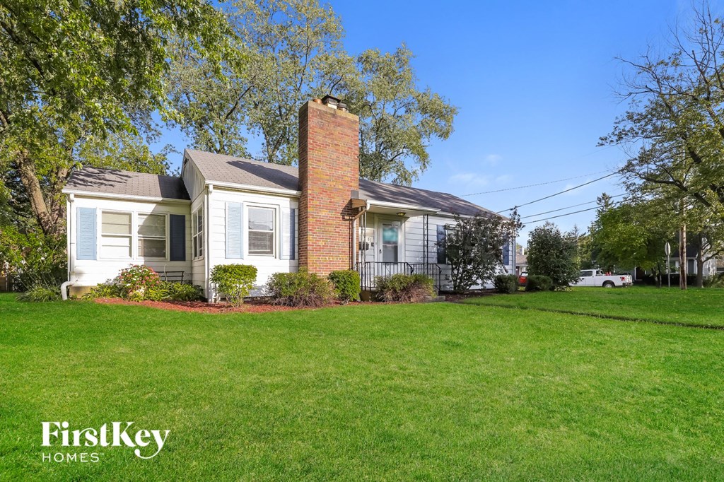 a white house with a green lawn and a brick chimney