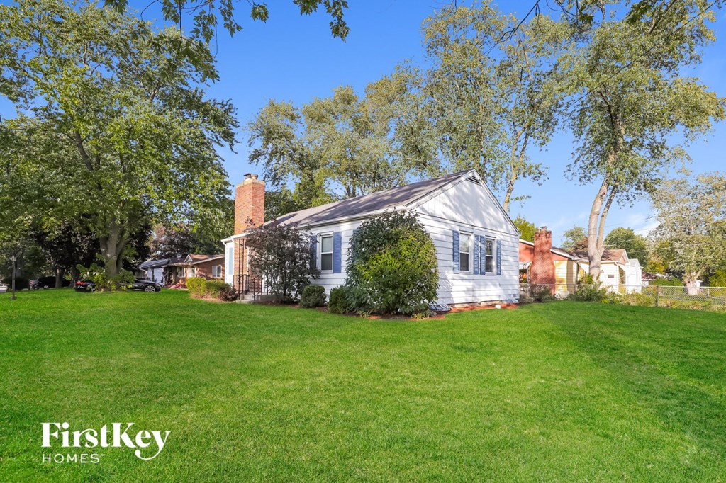 a white house with a green lawn and trees
