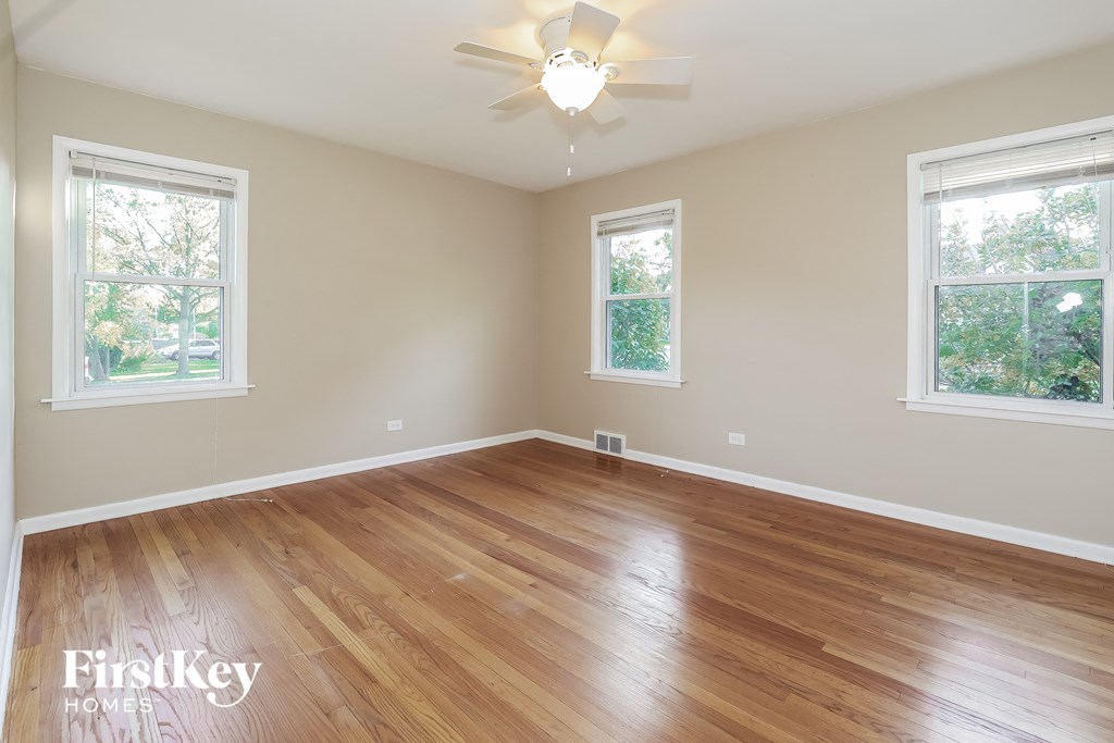an empty living room with wood floors and a ceiling fan