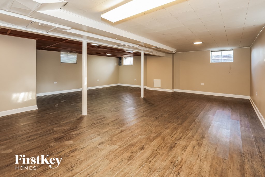 an empty basement with a wood floor and white pillars