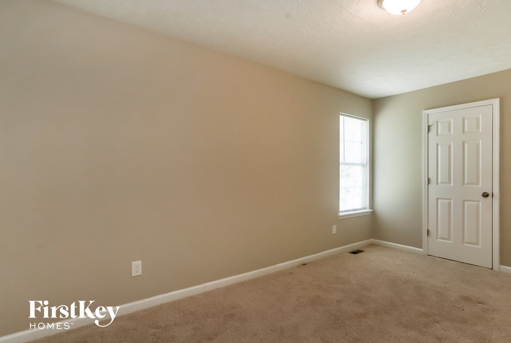 a bedroom with a white door and a carpeted floor