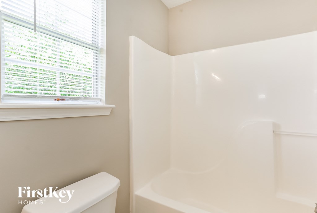 a bathroom with a tub and a window and a toilet