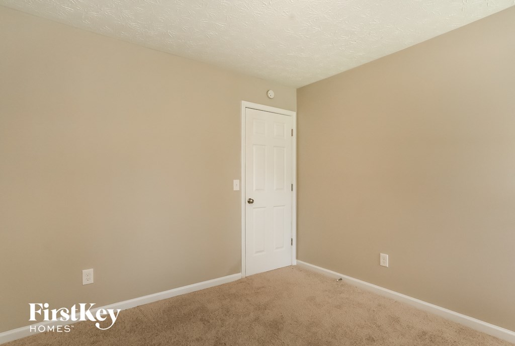 a bedroom with beige carpet and a white door