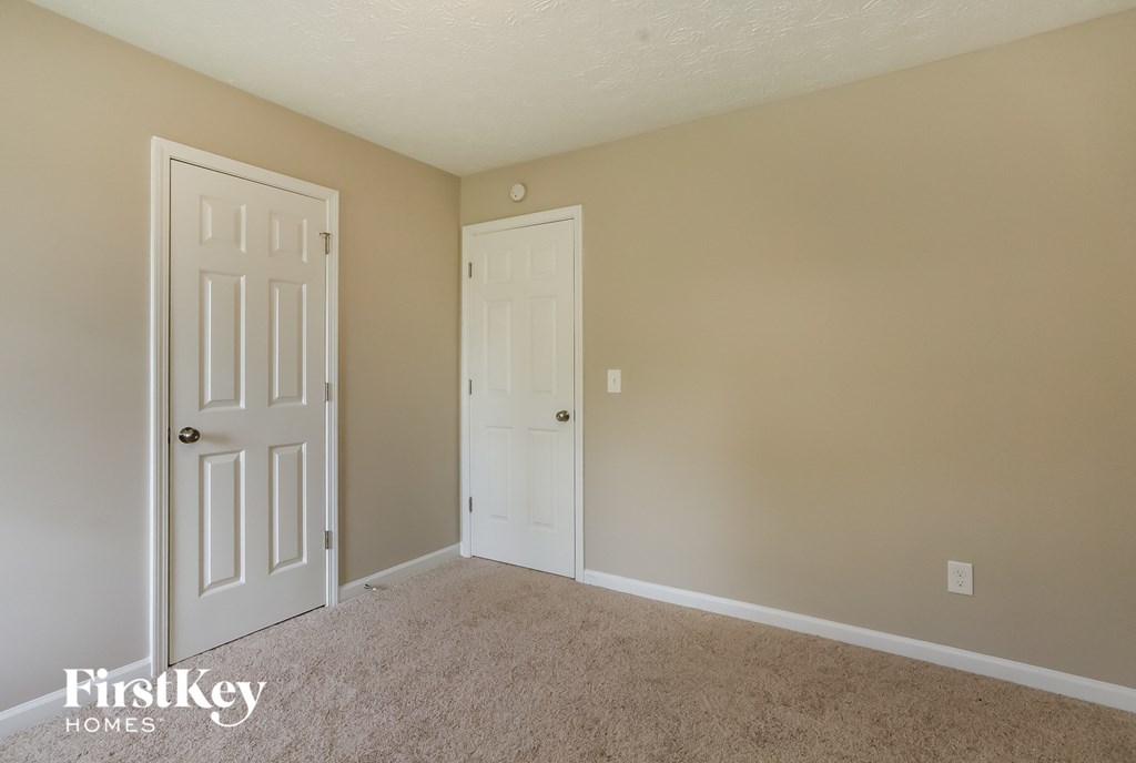 a bedroom with two doors and a carpeted floor
