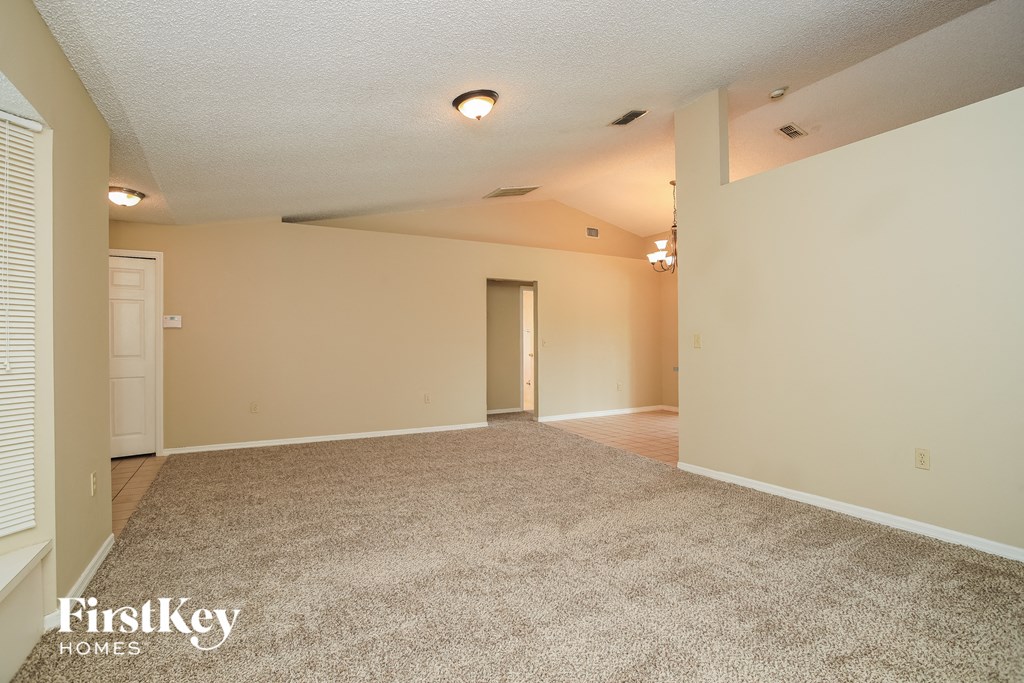 A carpeted room with a door and a window.