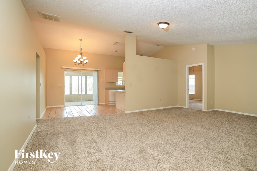A spacious room with a carpeted floor and a chandelier hanging from the ceiling.