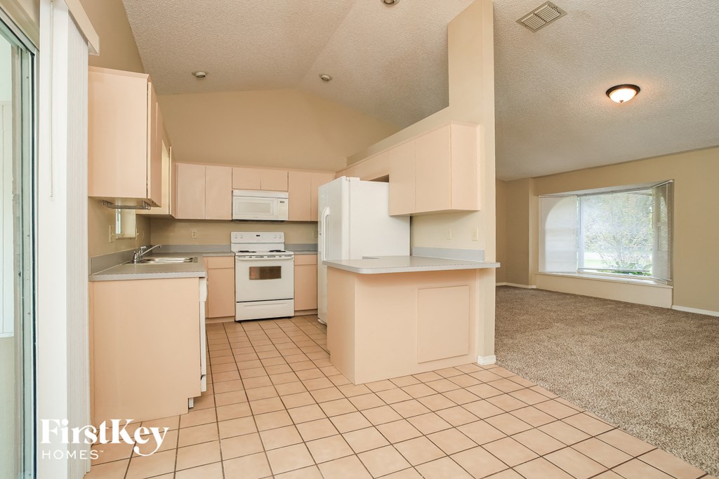 A kitchen with a white stove top oven and a white refrigerator.