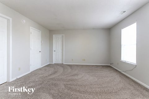 a spacious living room with carpet and white walls