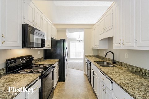 a kitchen with white cabinets and granite counter tops