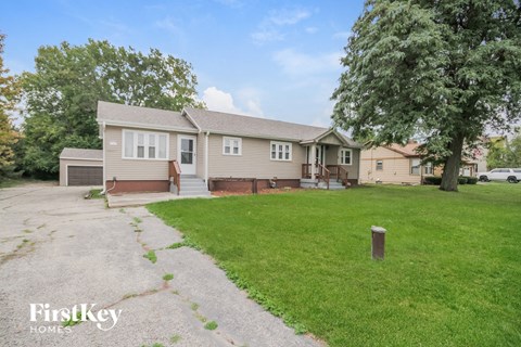 A house with a driveway and a tree in front of it.