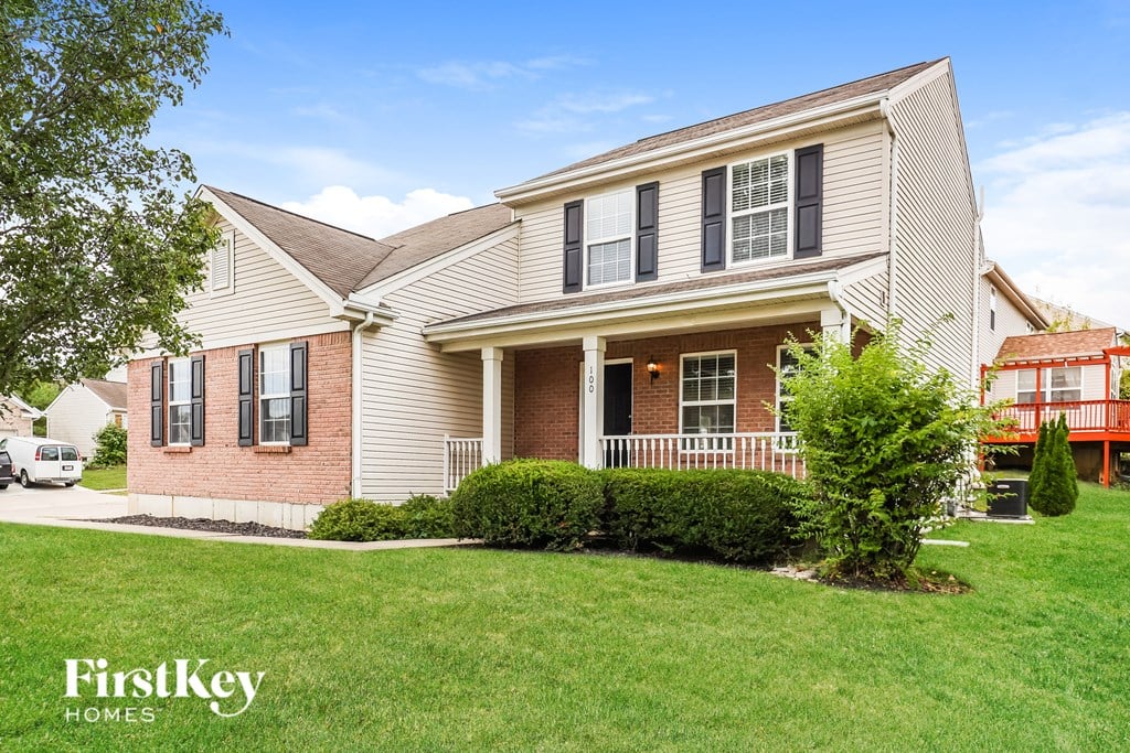 A house with a white picket fence and a tree in front of it.