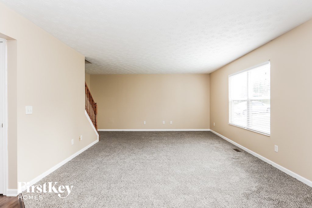A room with a carpeted floor and a window with blinds.