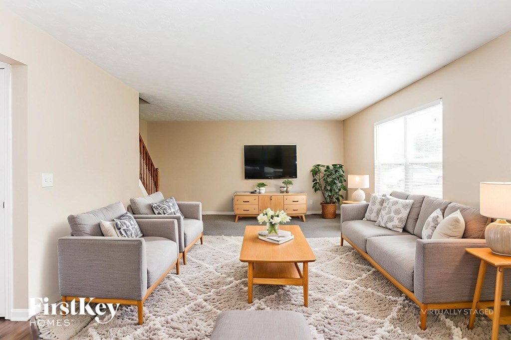 A living room with a grey couch, a wooden coffee table, and a flat screen TV mounted on the wall.
