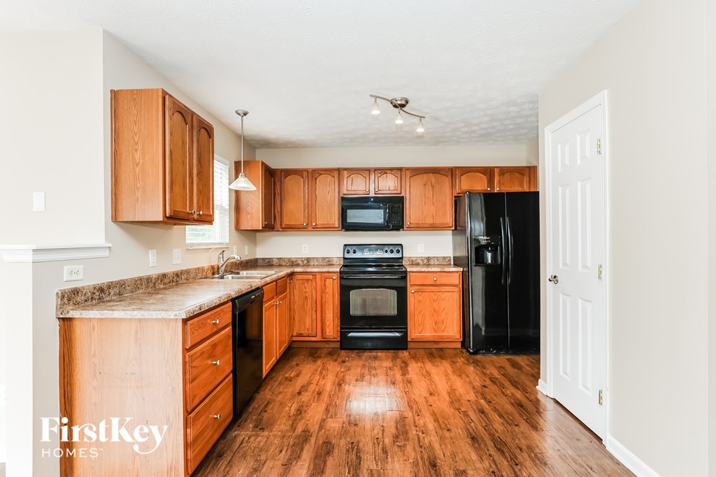 A kitchen with wooden cabinets and a black refrigerator.