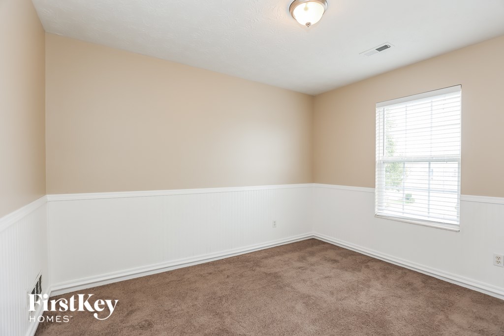 A room with a carpeted floor and a window with blinds.