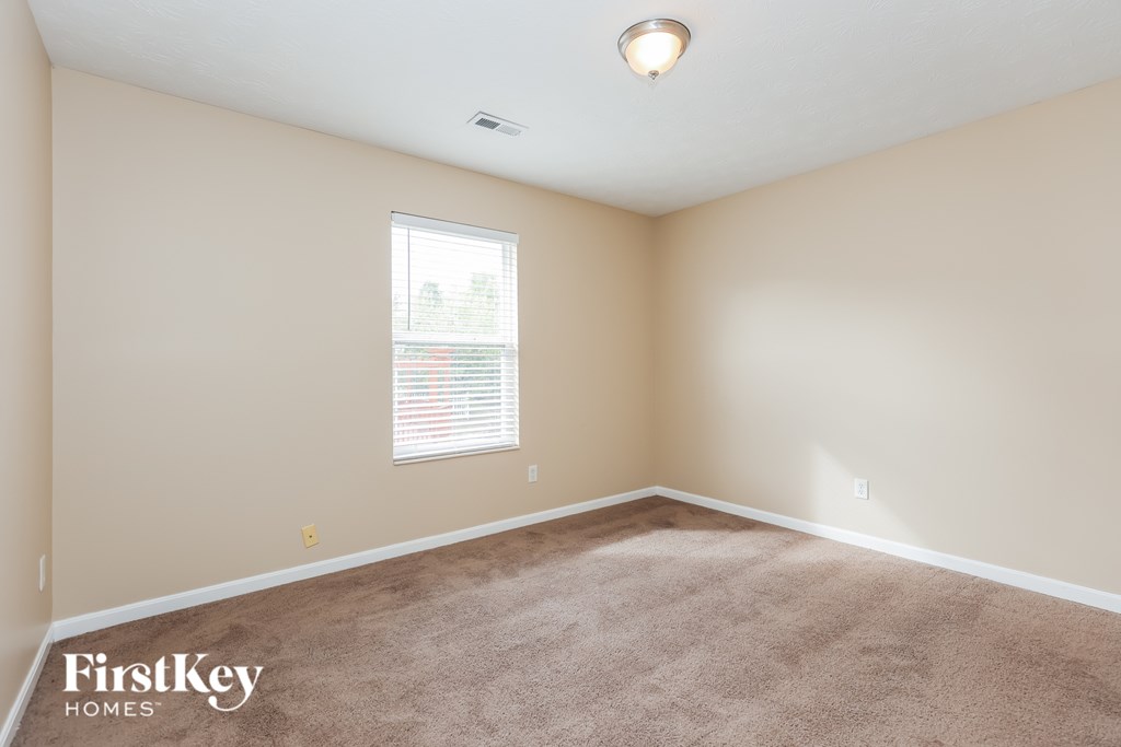 A room with a carpeted floor and a window with blinds.