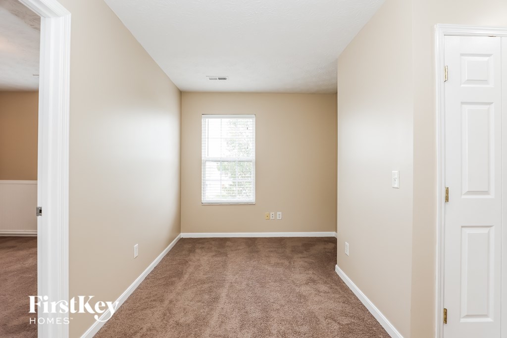 A room with a carpeted floor and a window with blinds.