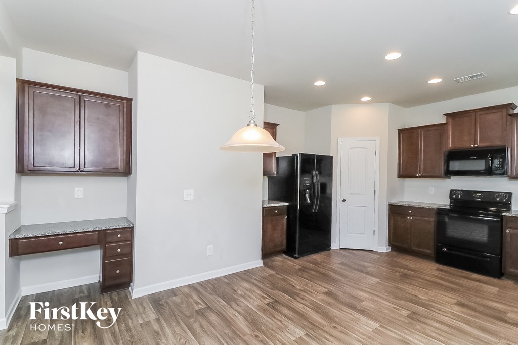 A kitchen with wooden floors and a black refrigerator.