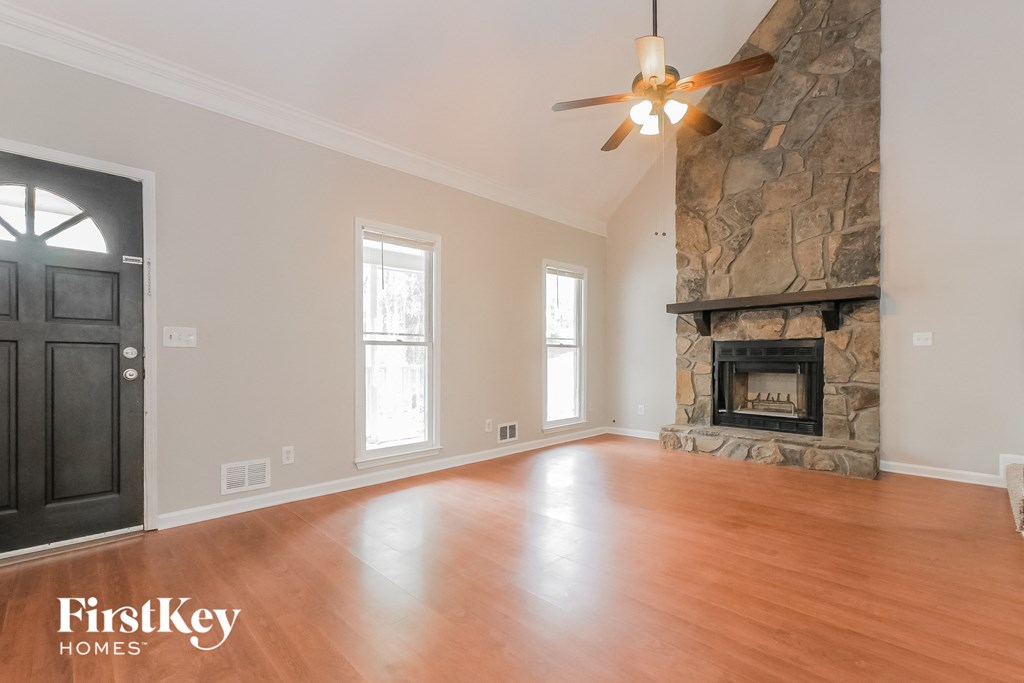 an empty living room with a fireplace and a ceiling fan