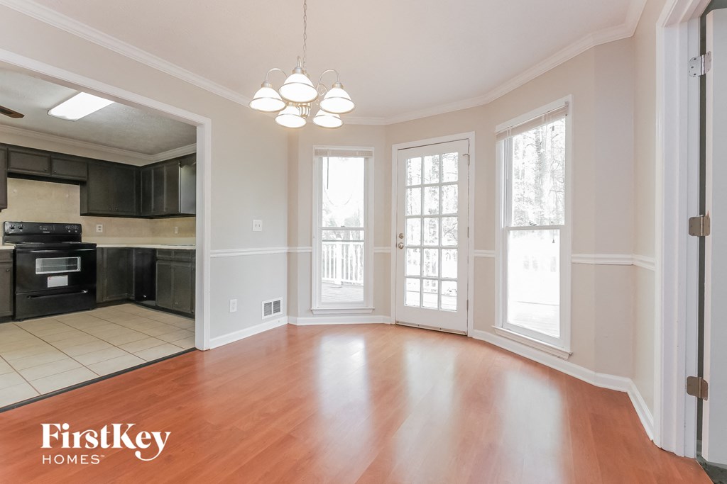 an empty living room with wood floors and a kitchen