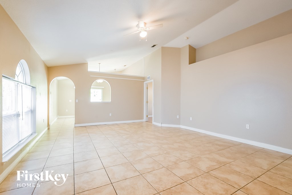 A spacious room with beige tiled flooring and white walls.
