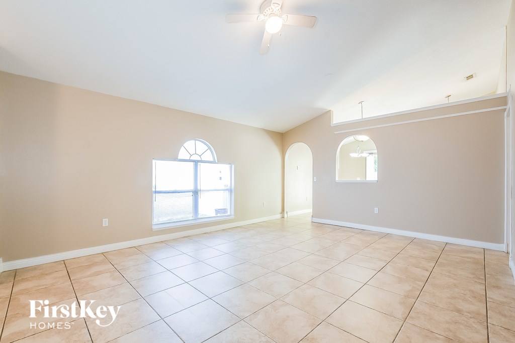 A spacious room with a ceiling fan and two windows.