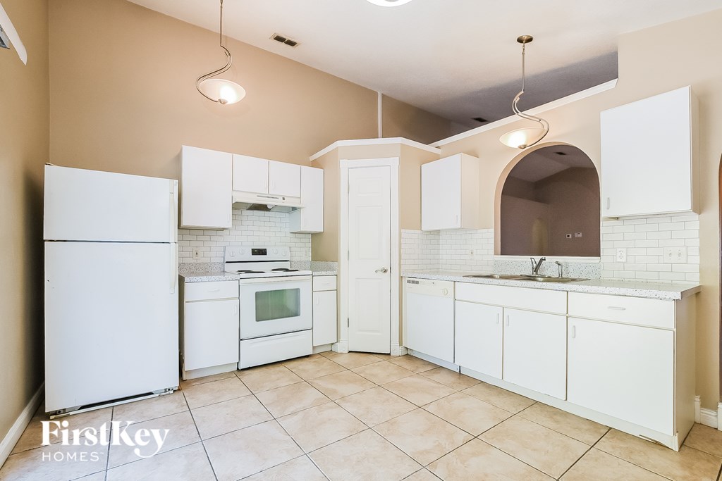 A kitchen with white appliances and cabinets.