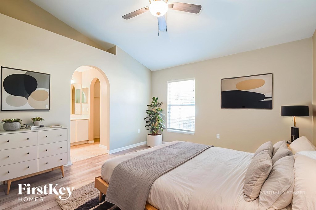 A bedroom with a bed, dresser, and ceiling fan.
