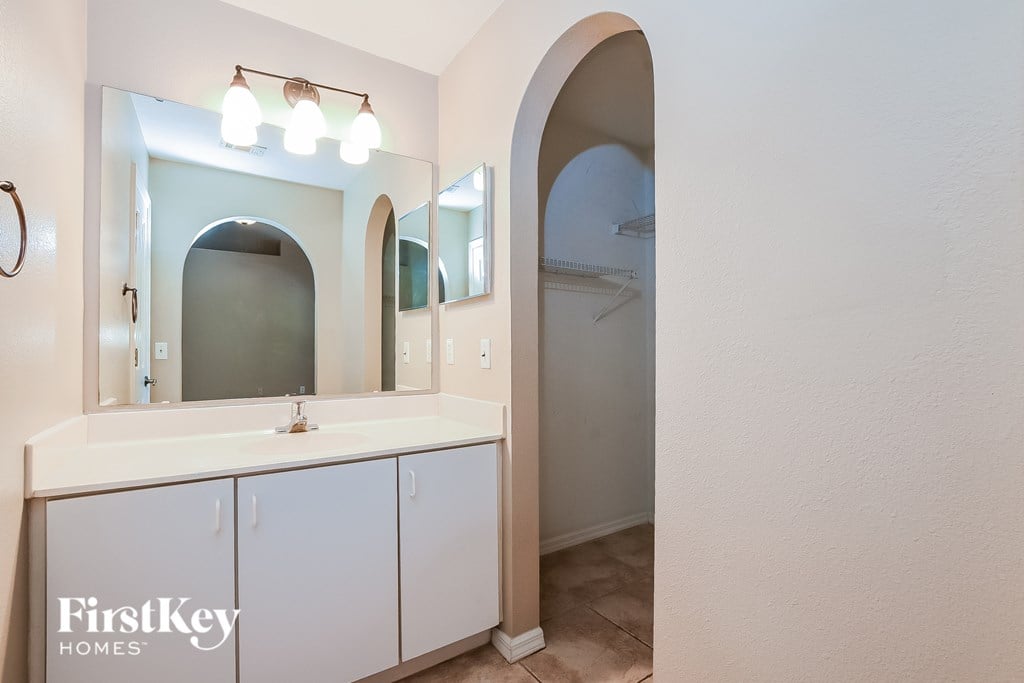 A bathroom with a white counter and a mirror above it.