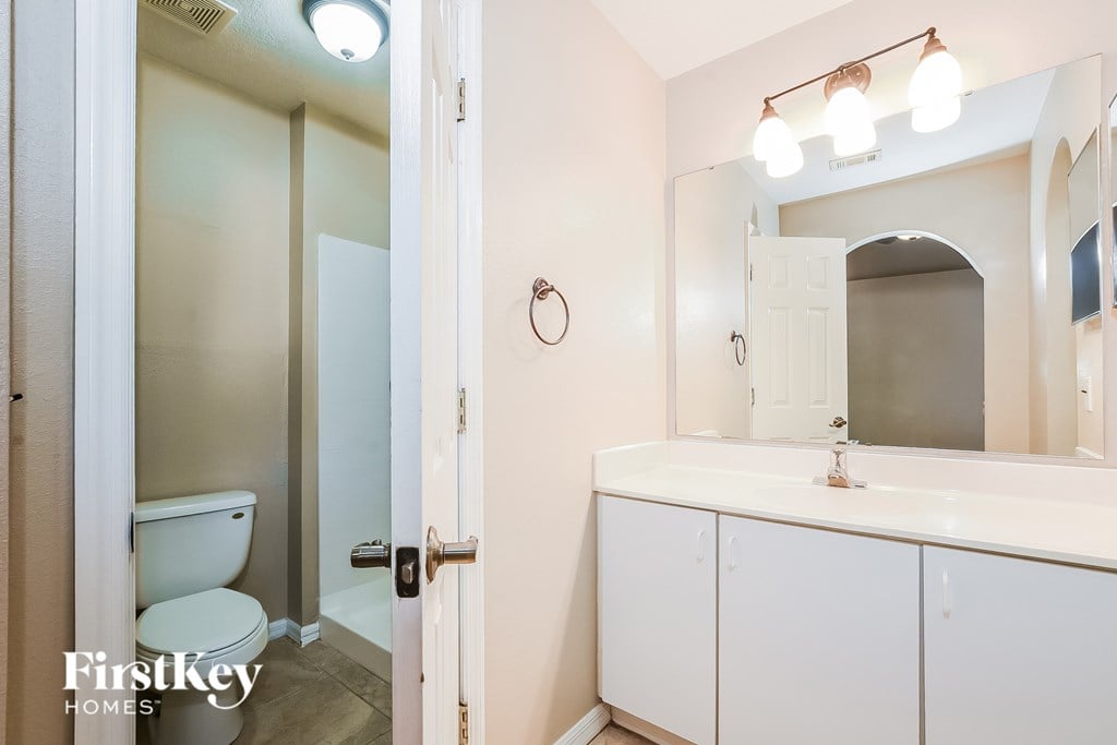 A bathroom with a toilet, sink, and mirror.