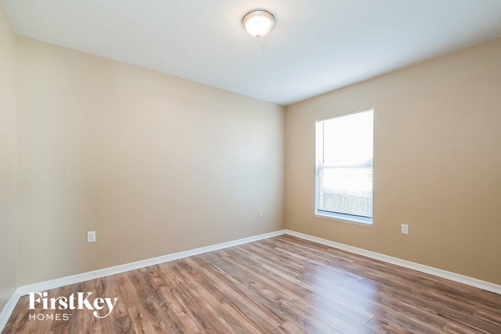 A room with wooden flooring and a window with blinds.