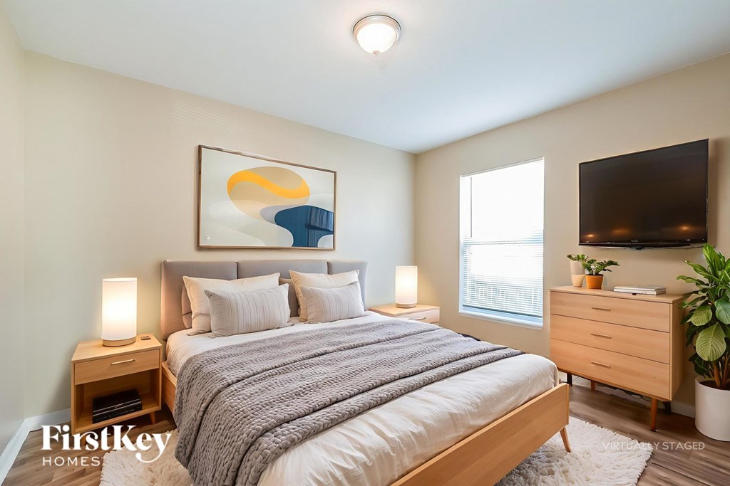 A bedroom with a bed, nightstands, and a painting on the wall.