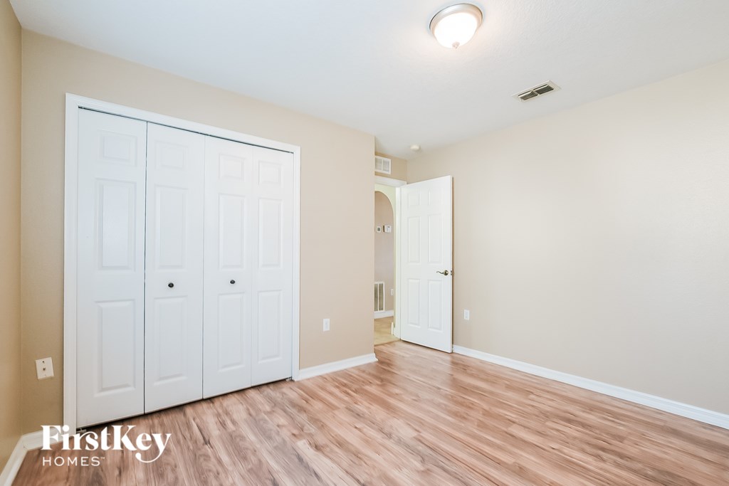 A room with a white door and a wooden floor.