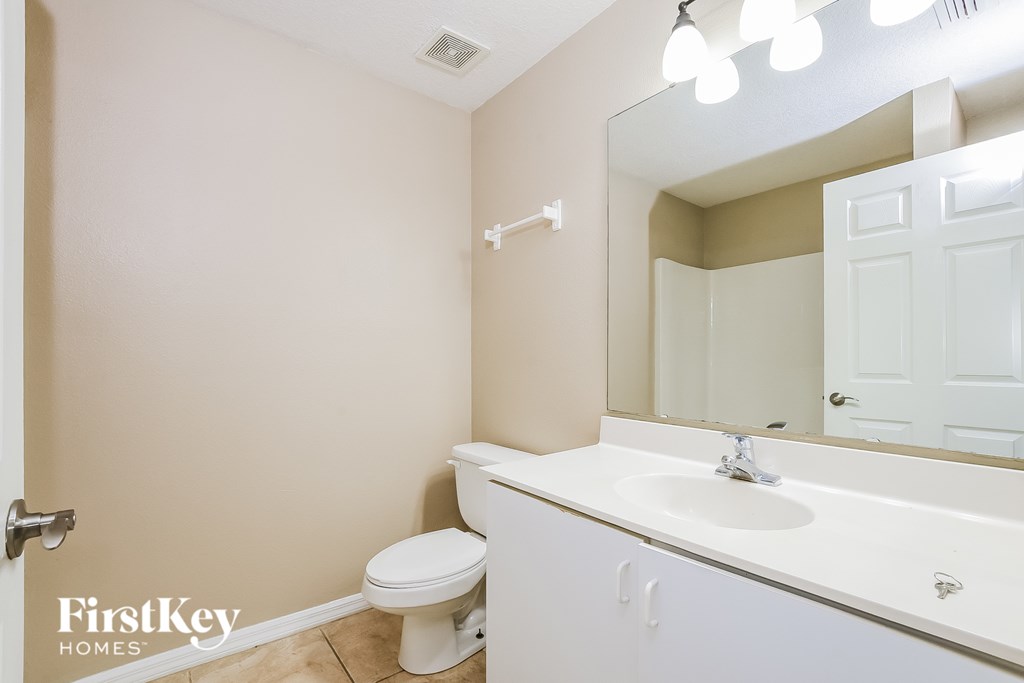 A bathroom with a toilet, sink and mirror.