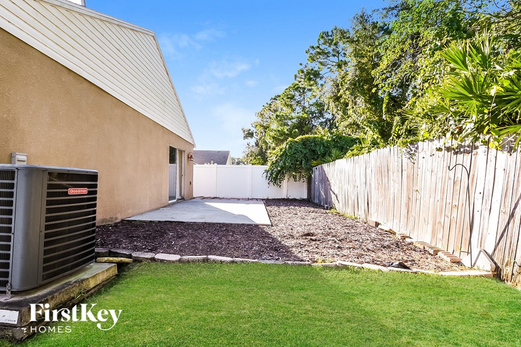 A tan house with a green lawn and a wooden fence.