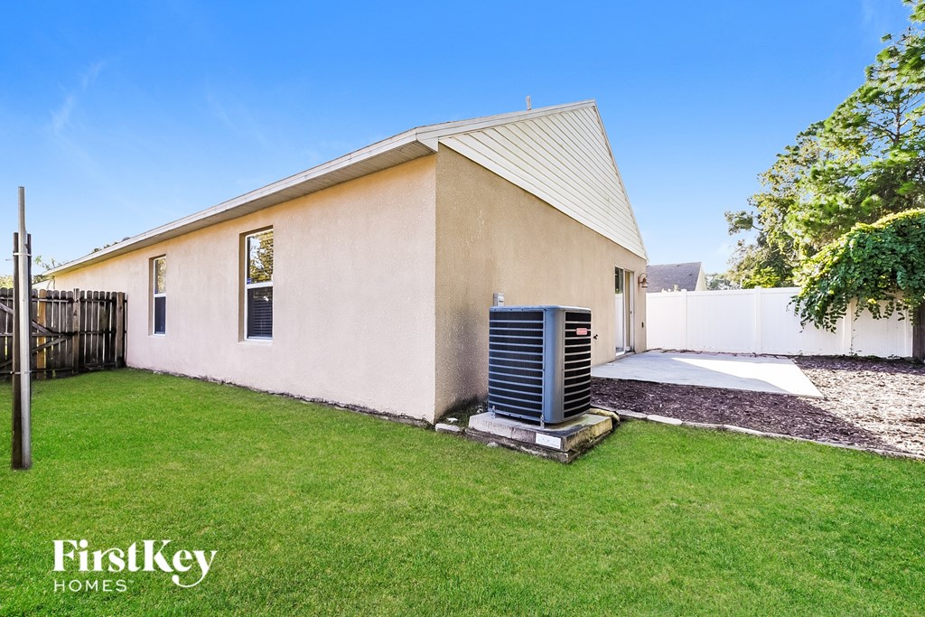 A small house with a metal air conditioning unit in the yard.